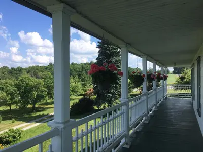 a porch with flowers and a view of the woods at Au Coeur des Jardins in Compton