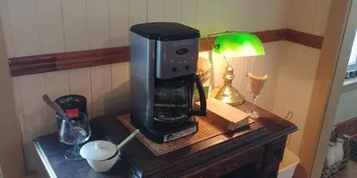 a coffee maker on top of a wooden table at Au Coeur des Jardins in Compton