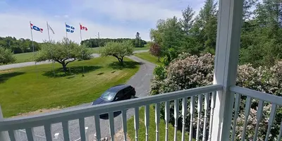 a car driving down a road with flags on a balcony at Au Coeur des Jardins in Compton