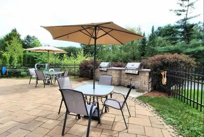 a patio with tables and chairs and an umbrella at Le Champlain Condo-Hôtel in Bromont