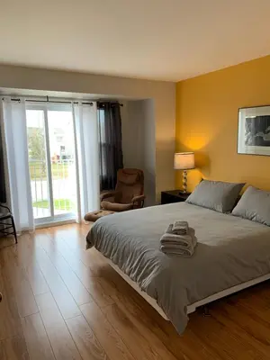 a bedroom with a bed and a chair and a window at Le Paréo de Magog-Mont Orford in Magog-Orford