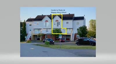 a large building with a yellow arrow on it at Le Paréo de Magog-Mont Orford in Magog-Orford