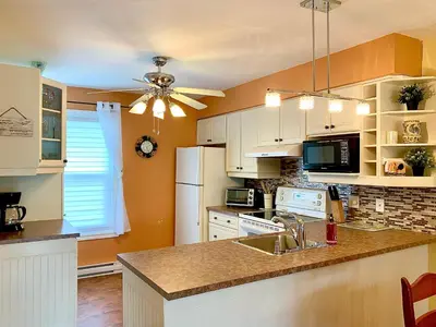 a kitchen with white cabinets and a ceiling fan at Le Paréo de Magog-Mont Orford in Magog-Orford