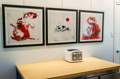 a counter with a toaster and four paintings on a wall at Au Loup, maison élégante in Waterloo