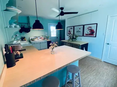 a kitchen with blue walls and a counter with stools at Au Loup, maison élégante in Waterloo