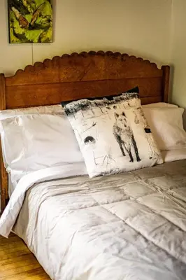 a bed with white sheets and a pillow on it at Au Loup, maison élégante in Waterloo