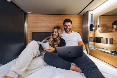 a man and a woman sitting on a bed with a laptop at Hygie Boutique Hotel in Montréal