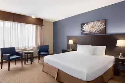 a hotel room with a bed and a table and chairs at Days Inn by Wyndham Montreal Airport Conference Centre in Dorval