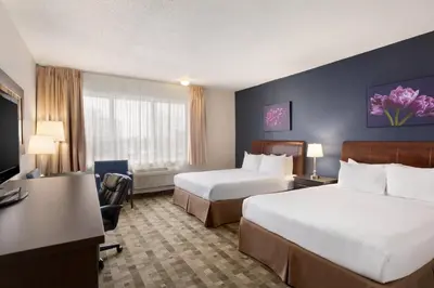 a hotel room with two beds and a desk at Days Inn by Wyndham Montreal Airport Conference Centre in Dorval