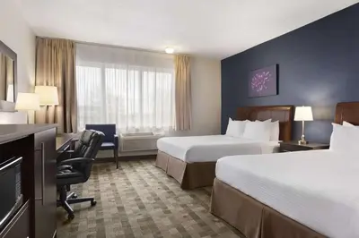 a hotel room with two beds and a desk at Days Inn by Wyndham Montreal Airport Conference Centre in Dorval