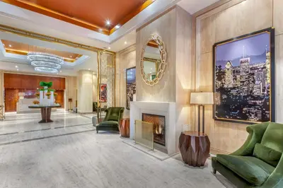 a lobby with a fireplace and green chairs at Omni Mont-Royal Hotel in Montréal