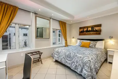 a bedroom with a bed and a desk and windows at Samesun Montreal Hotel & Hostel in Montréal