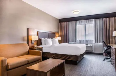 a hotel room with a bed and a couch at Quality Hotel Dorval Aeroport in Dorval