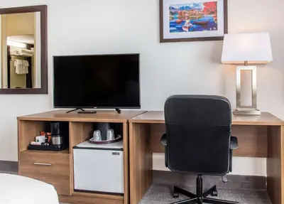 a bedroom with a desk with a television and a chair at Quality Hotel Dorval Aeroport in Dorval