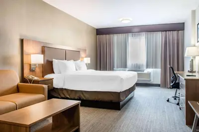 a large hotel room with a large bed and a desk at Quality Hotel Dorval Aeroport in Dorval