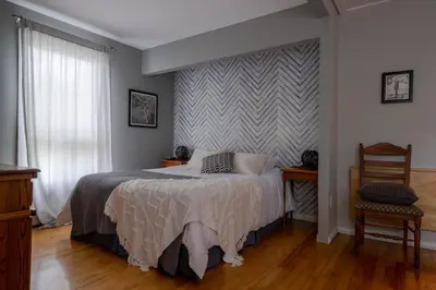a bedroom with a bed and a striped wall at Au coq du bonheur in Magog-Orford