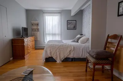 a bedroom with a bed and a chair and a glass table at Au coq du bonheur in Magog-Orford