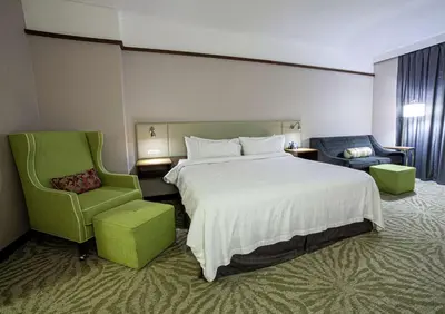 a hotel room with a bed and a chair at Hilton Garden Inn Montreal Airport in Dorval
