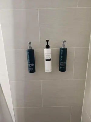 three bottles ofodorizers sit on a shelf in a bathroom at Hilton Garden Inn Montreal Airport in Dorval