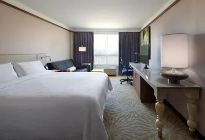 a hotel room with a bed and a desk with a lamp at Hilton Garden Inn Montreal Airport in Dorval