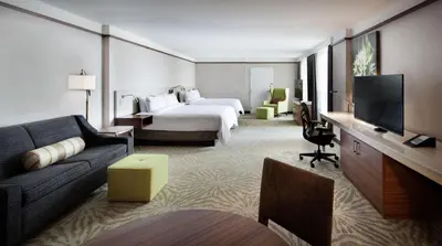 a hotel room with a bed and a couch and a tv at Hilton Garden Inn Montreal Airport in Dorval