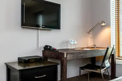 a desk with a television on a wall with a chair at Auberge de La Fontaine in Montréal