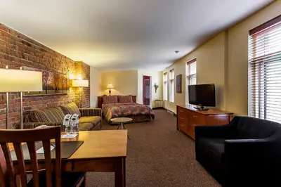 a hotel room with a couch and a bed and a tv at Auberge de La Fontaine in Montréal
