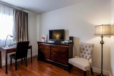 a hotel room with a desk and a television and a chair at Auberge de La Fontaine in Montréal