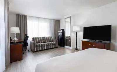 a hotel room with a bed and a flat screen tv at Le Nouvel Hotel in Montréal