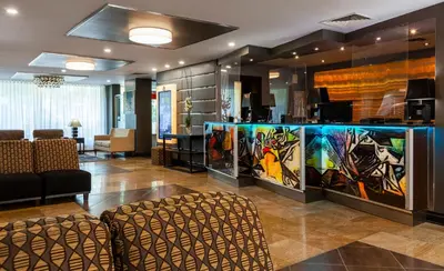 a lobby with a bar with paintings on the wall at Le Nouvel Hotel in Montréal