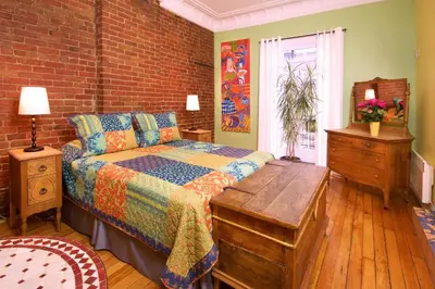 a bedroom with a bed and a brick wall at Auberge Les Bons Matins in Montréal