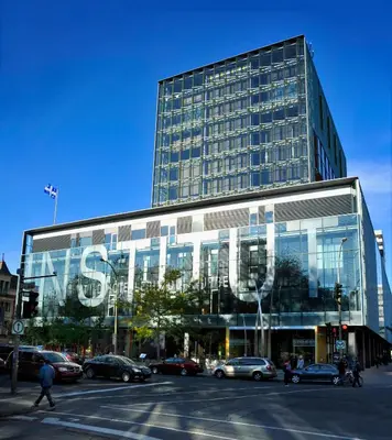 a large glass building with cars parked in front of it at Hôtel de l'ITHQ in Montréal
