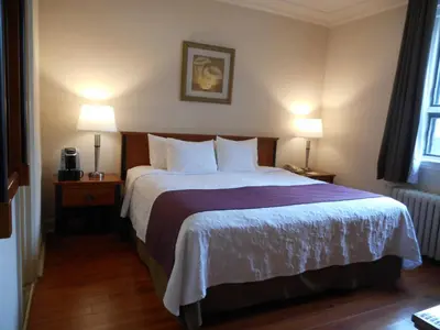 a hotel room with a large bed with two lamps at Hotel St-Denis in Montréal