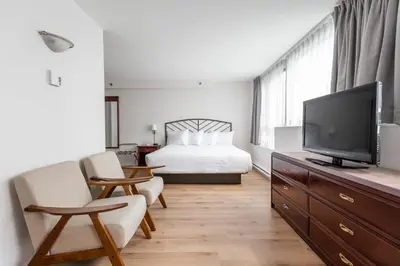 a bedroom with a bed and a flat screen tv at Hotel les Suites Labelle in Montréal