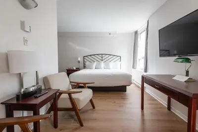 a hotel room with a bed and a desk and chair at Hotel les Suites Labelle in Montréal