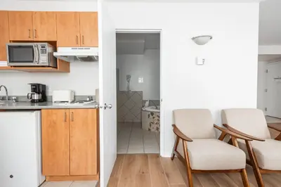 a kitchen with wooden cabinets and two chairs in a room at Hotel les Suites Labelle in Montréal