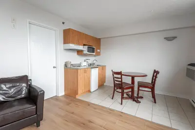 a living room with a table and chairs and a kitchen at Hotel les Suites Labelle in Montréal