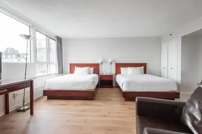 a hotel room with two beds and a couch at Hotel les Suites Labelle in Montréal