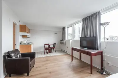 a living room with a television and a desk with a chair at Hotel les Suites Labelle in Montréal