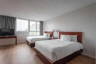 a hotel room with two beds and a flat screen tv at Hotel les Suites Labelle in Montréal