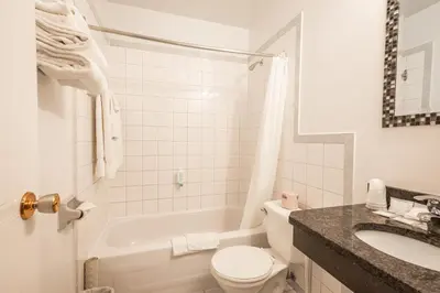 a white bathroom with a toilet and a sink at Hotel le Roberval in Montréal