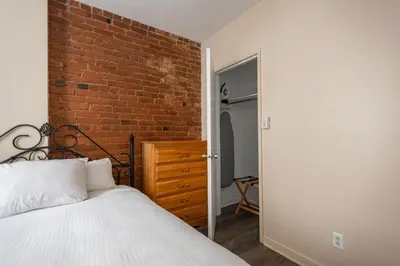 a bedroom with a brick wall and a bed at Hotel le Roberval in Montréal