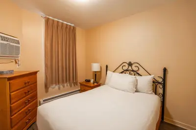 a bedroom with a bed and a dresser and a window at Hotel le Roberval in Montréal