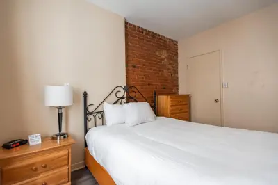 a bedroom with a white bed and a brick wall at Hotel le Roberval in Montréal