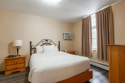 a bedroom with a white bed and a window at Hotel le Roberval in Montréal