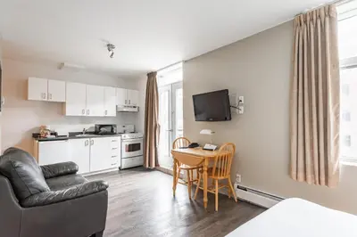 a living room with a couch and a table and a kitchen at Hotel le Roberval in Montréal