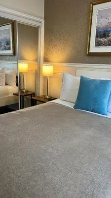 a bedroom with a bed with two lamps and a mirror at Parc Suites Hotel in Montréal