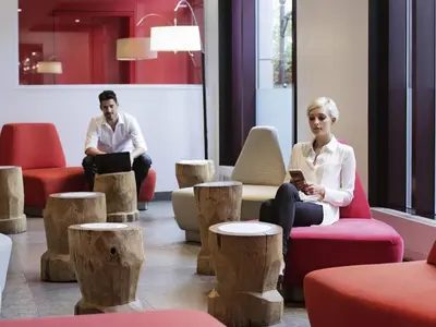 two people sitting in a room with wooden stools at Novotel Montreal Center in Montréal