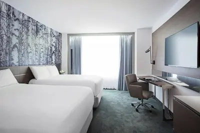 a hotel room with two beds and a desk and a tv at Novotel Montreal Center in Montréal