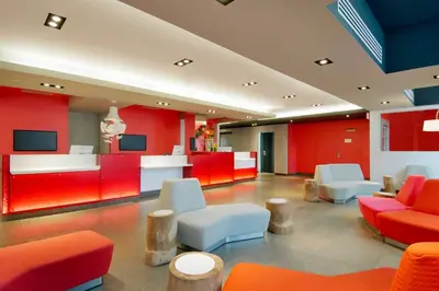 a lobby with red and white chairs and tables at Novotel Montreal Center in Montréal